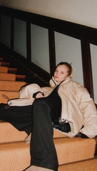 Paula sitzt in Winterjacke auf einer Treppe | Quelle: