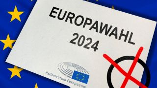 Ein Europawahl-2024-Brief, dahinter die EU-Flagge (Quelle: IMAGO | Bihlmayerfotografie)